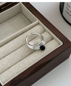 Détail d'une bague ouverte argentée multicouche ornée d'une perle ronde en agate noire