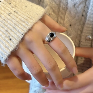 Bague rétro multicouche en argent avec onyx noir portée avec un pull en tricot blanc doux