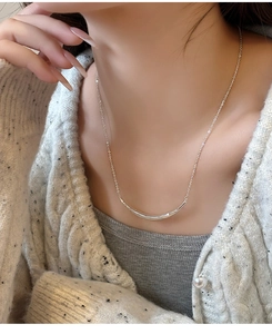 Vue détaillée d'un collier pendentif sourire argenté porté sur la clavicule