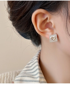 Gros plan de boucles d'oreilles carrées argentées avec cœur et texture à carreaux
