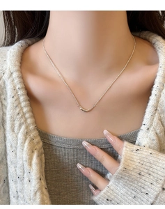 Gros plan d'un collier sourire en argent minimaliste avec pendentif courbe sur mannequin