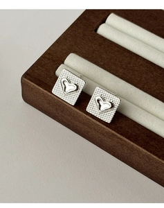 Vue détaillée de boucles d'oreilles carrées en argent avec motif cœur sur présentoir