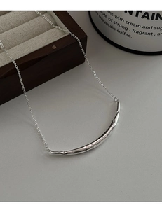 Gros plan du collier à pendentif arc argenté exposé sur une boîte à bijoux en bois
