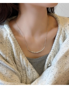 Vue macro d'un collier pendentif sourire argenté avec texture martelée sur une clavicule
