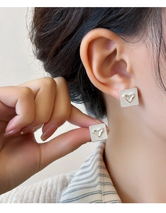 Gros plan de boucles d'oreilles carrées argentées avec motif à carreaux et cœur 3D