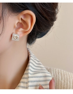 Gros plan d'une boucle d'oreille carrée argentée avec texture quadrillée sur mannequin