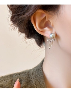 Detail of elegant grey pearl earrings with silver ribbon bow on model's ear