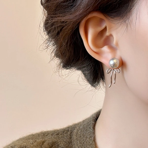 Elegant Korean style grey pearl stud earrings with silver ribbon bow on model's ear