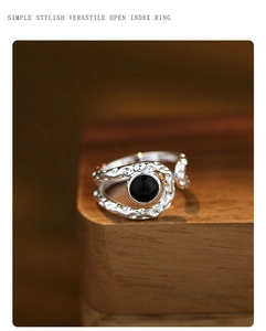 Detail view of silver lava texture ring with black onyx stone on a wooden display