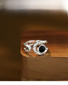 Detail of silver textured ring with black agate stone inlay on a wooden surface