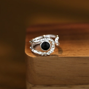 Lava texture silver ring with black agate stone set on a natural wooden surface