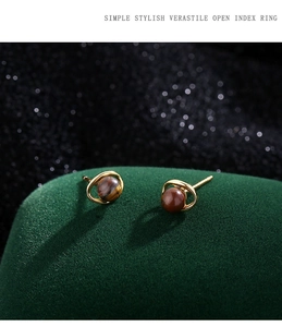 Détail de boucles d'oreilles en œil de tigre doré sur velours vert avec effet bokeh
