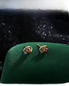 Gros plan de boucles d'oreilles œil de tigre vintage avec anneaux dorés sur velours