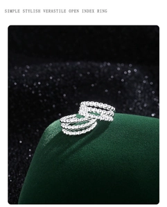 Détail macro d'une bague ouverte multicouche argentée sur un support en velours vert