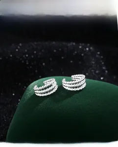 Détail des boucles d'oreilles argentées à perles sur fond en velours vert foncé