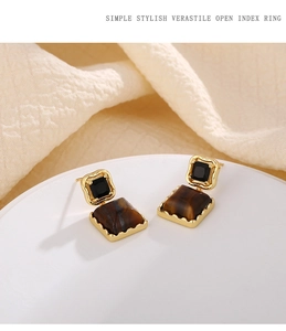 Detail of vintage gold earrings with black gemstone and rectangular tiger eye stone inlay