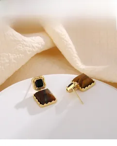 Detailed view of square tiger eye earrings with gold metal frame and marble texture