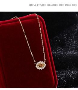 Detailed macro of golden Evil Eye necklace featuring Tiger Eye stone on red velvet