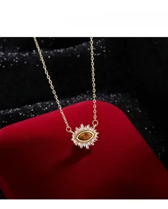 Detail of gold evil eye necklace with tiger eye stone on red velvet background