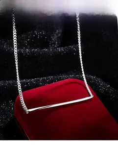 Close-up of silver minimalist bar necklace displayed on a red velvet jewelry box