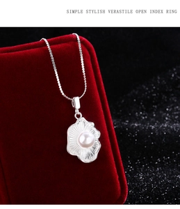 Macro shot of shell textured silver pendant with white pearl on red velvet box
