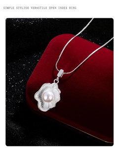 Macro view of shell-shaped silver necklace with a central pearl on red velvet box