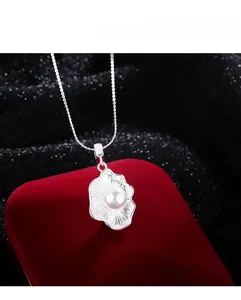 Detail of shell flower pearl pendant with brushed silver finish on a red velvet jewelry box