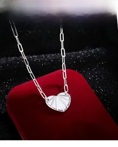 Dettaglio collana a graffetta argento con pendente a cuore su scatola porta gioie rossa