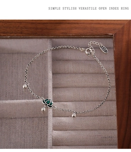 Close-up of S925 sterling silver anklet with green enamel lotus charm on velvet display