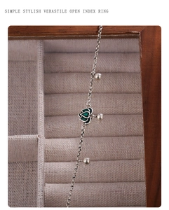 Detailed macro view of silver green lotus pendant and bead charms on a subtle cross chain