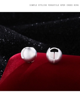 Detail view of matte silver spherical earrings on luxury red velvet stand with dark background