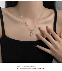 Silver geometric hollow oval pendant necklace on a sleek snake chain worn by a female model