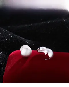 Macro detail of a matte silver-finish spherical open ring on a red velvet display stand