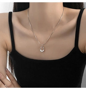 Detail of silver irregular hollow oval pendant on snake chain worn by a female model