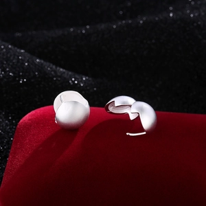Minimalist silver matte ball earrings with hinged clasp on a red velvet display