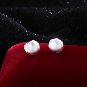 Minimalist matte silver ball hoop earrings featuring a brushed finish on a red velvet display