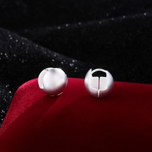 Minimalist matte silver spherical hoop earrings on a luxury red velvet display background