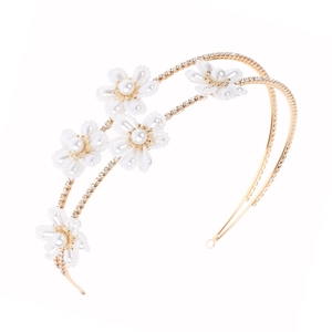 Detail of bridal headband featuring white pearl flowers and rhinestones on gold frame