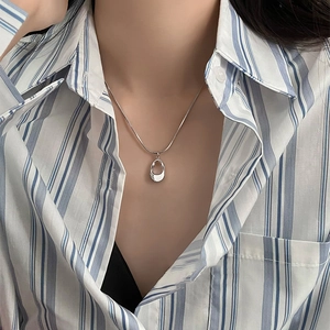 Minimalist irregular hollow oval pendant on a sleek silver snake chain worn by a model