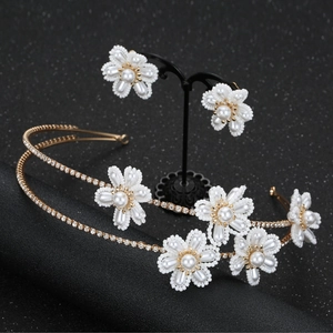 Detail of bridal headband and clip earrings with white pearls and gold flower motifs