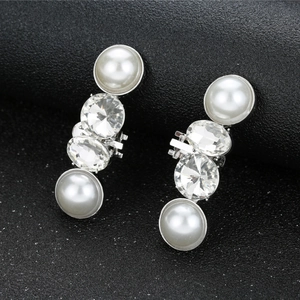 Elegant silver earrings with pearls and rhinestones on a dark textured background