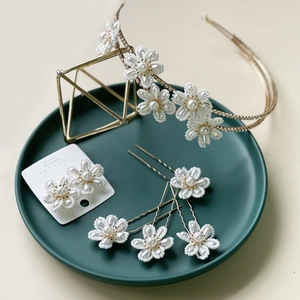 Detail of bridal hair set with white beaded flowers, pearl earrings and golden tiara