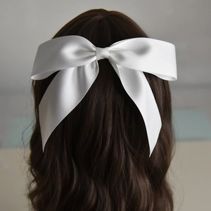 Detailed back view of a white satin bridal bow clip on long wavy brown hair