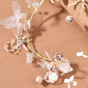 Detail of handmade floral headband with golden wire, lace butterflies and pink ribbons