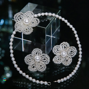 Detailed macro view of woven bridal jewelry set with pearl flower necklace and earrings
