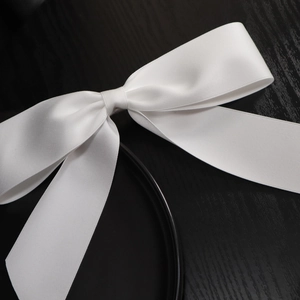 Detailed view of large white satin bow hair clip with smooth silk luster and texture