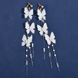 Close-up of elegant white fabric butterfly earrings with long pearl and rhinestone tassels
