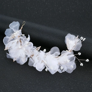 Détail de pince à cheveux mariée avec fleurs en tulle blanc, perles et fil doré sur noir
