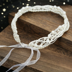 Détail d'un bandeau de mariée fait main avec perles et rubans en mousseline blanche