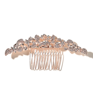 Close-up of rose gold bridal hair comb with intricate leaf patterns and sparkling rhinestones